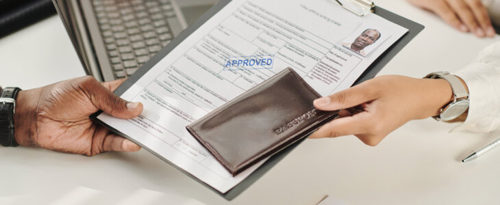 Close-up of man getting his approved documents for visa in visa agency