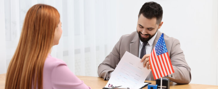 Immigration to United States of America. Embassy worker approving visa application form to woman in office