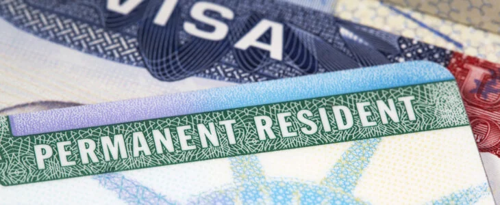 macro shot of a US green card with a passport visa in the background